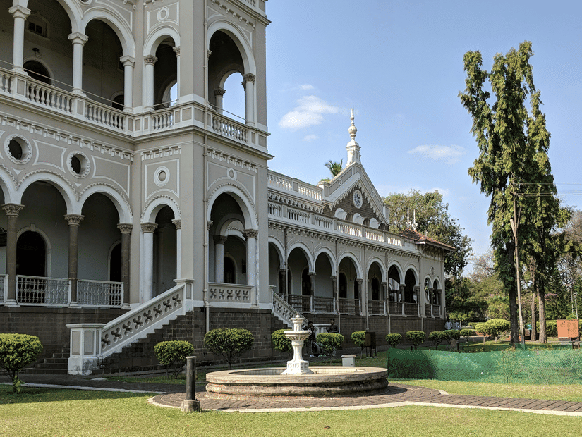 A facade image of Aga Khan Palace with a well maintained garden in the front.