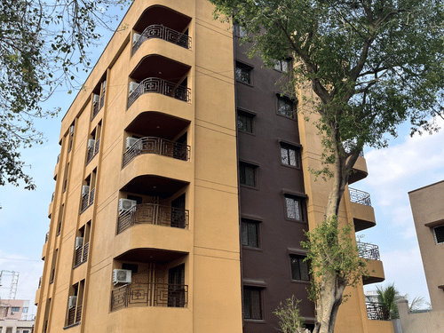 A multi-storey hotel building with curved balconies stands beside tall trees at VITS Select Kharadi, Pune.
