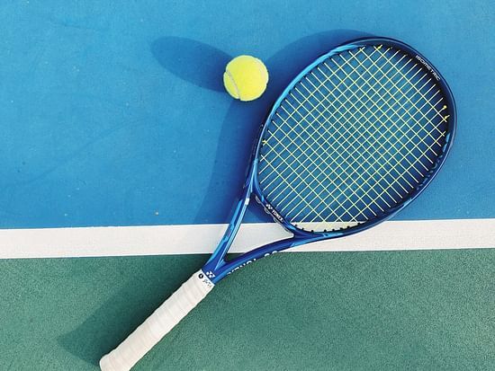 A tennis racket and yellow ball on a blue court, implying an active game or a break