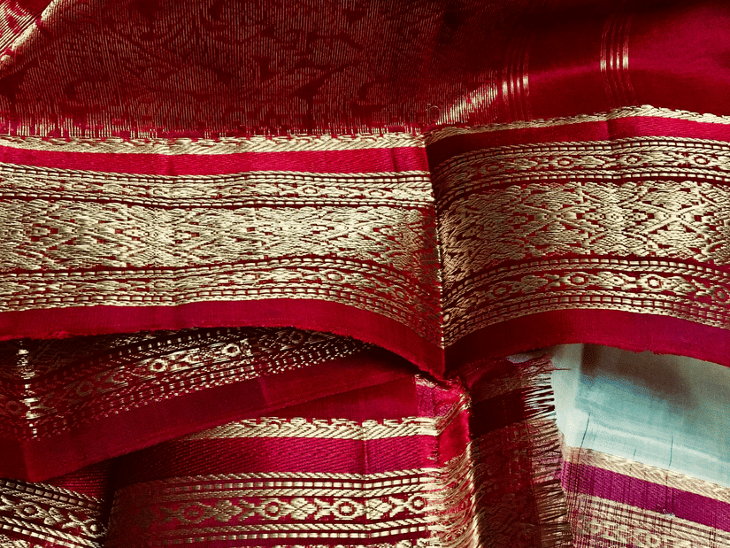 A silk saree with intricate gold zari brocade borders, traditional Indian textile shimmering under soft light
