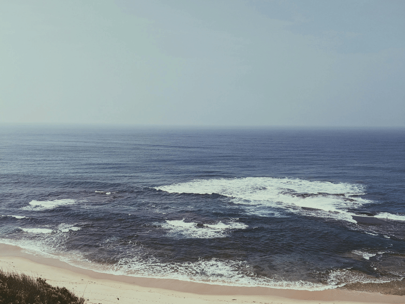 A beach with pristine waters, clean sands, and a cloudy sky where waves meet the shore, available through hotel packages in Mumbai