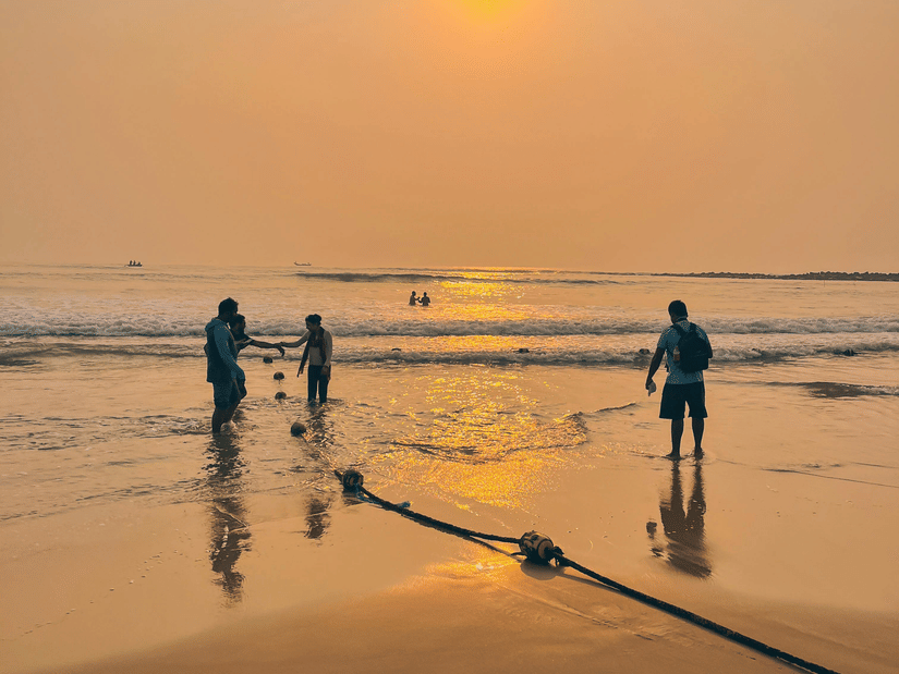 Silhouettes of people standing on a beach during a vibrant sunset.