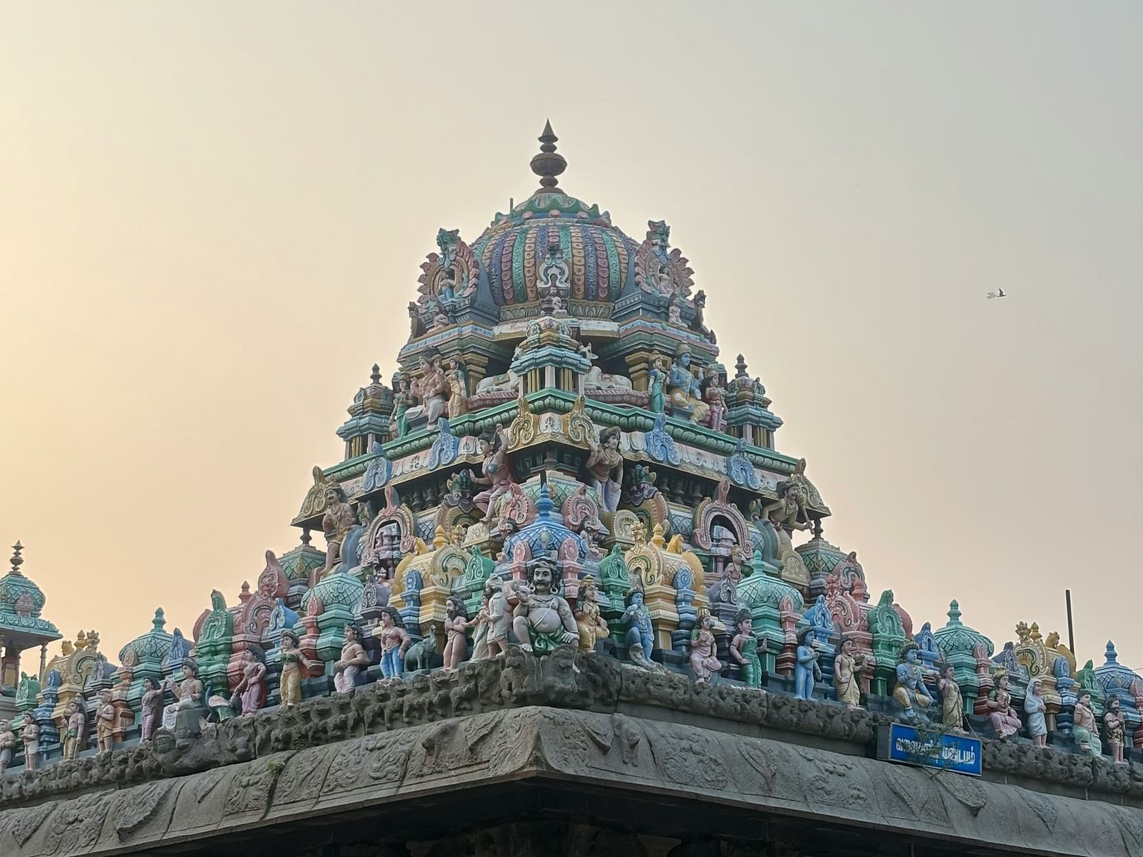 A close-up of a temple tower showcases intricate carvings against a plain sky.