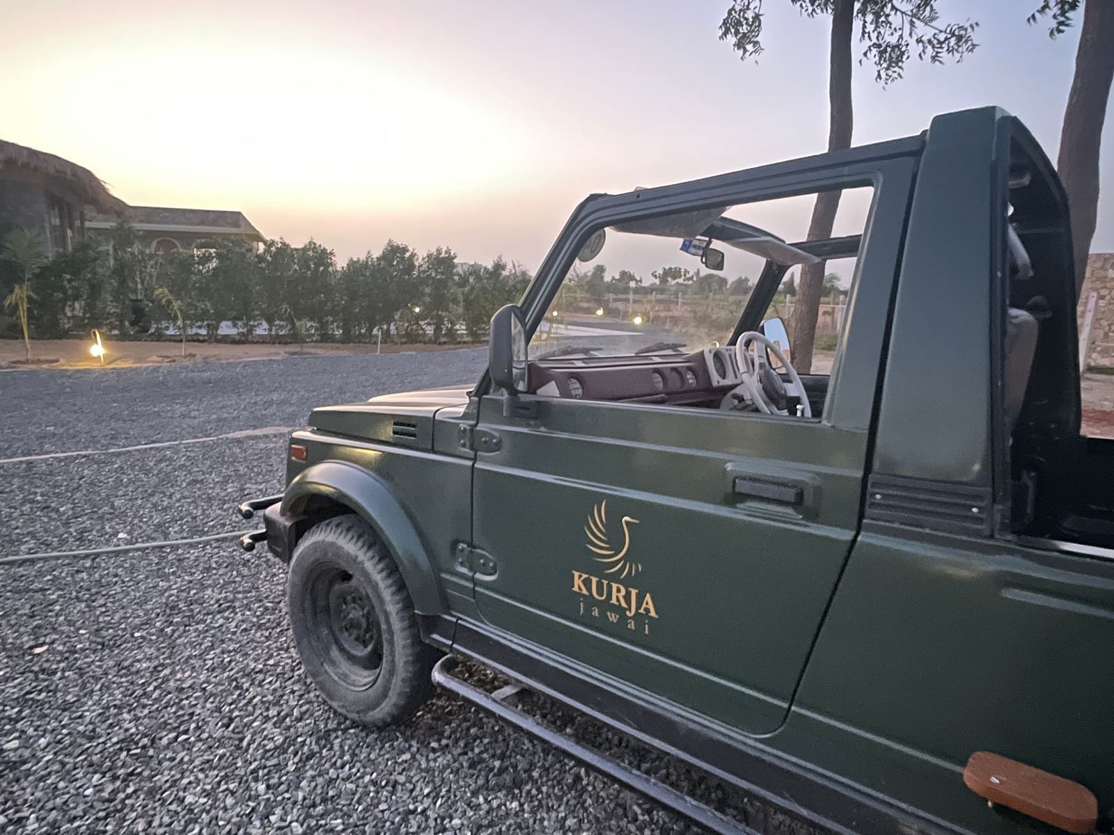 A  safari jeep with the logo of KURJA Jawai on it, facing a sky with sun rising