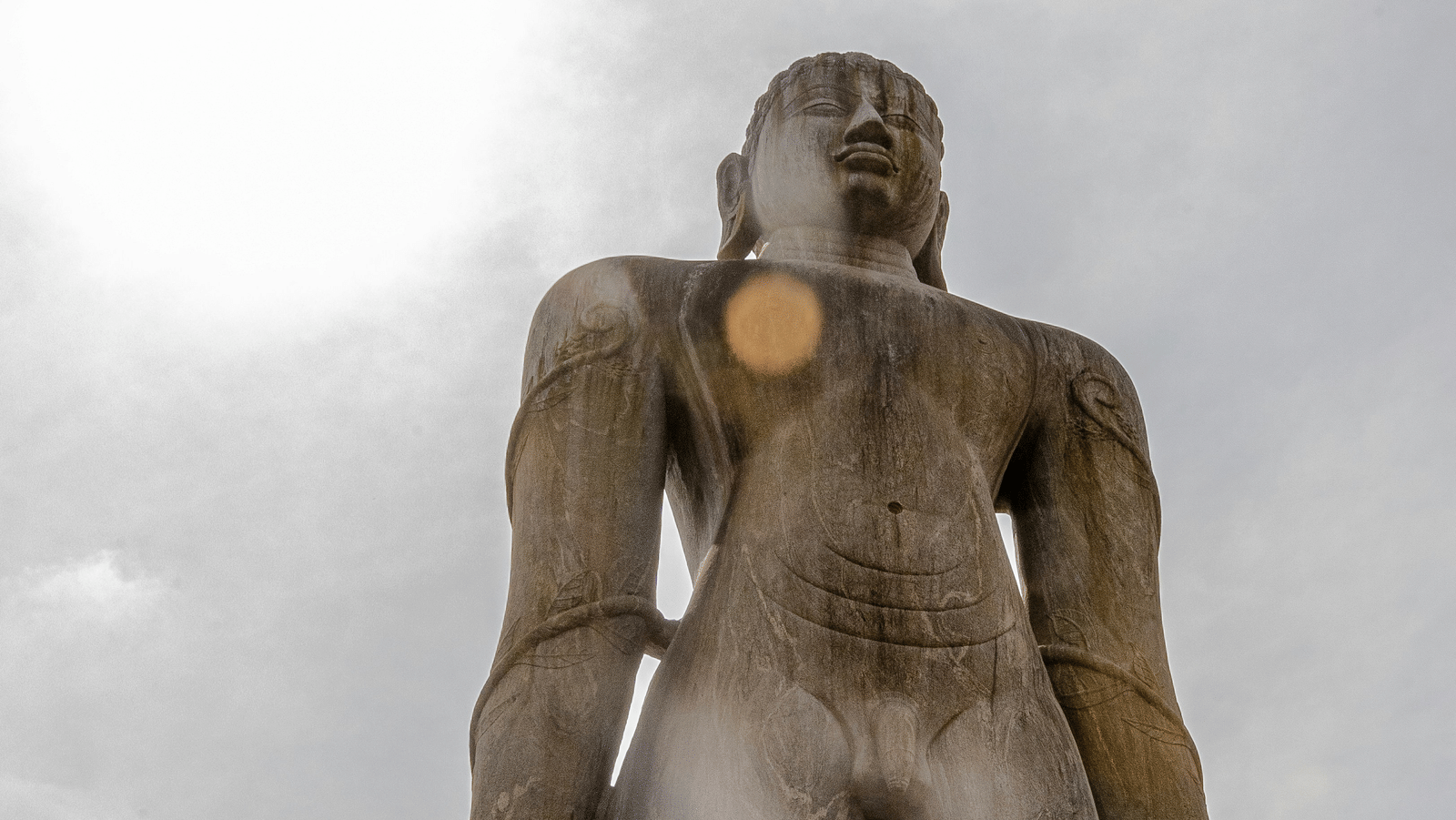 A view of the gommateshwara statue as seen from below with the sun shining in the background - Bangalore to Shravanabelagola.