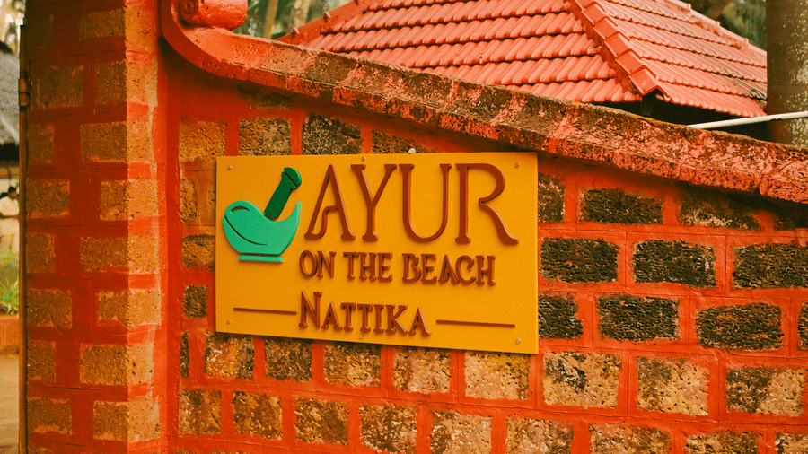 The resort entrance gate of Ayur On The Beach Nattika featuring a brick wall and a signage with the resort name.