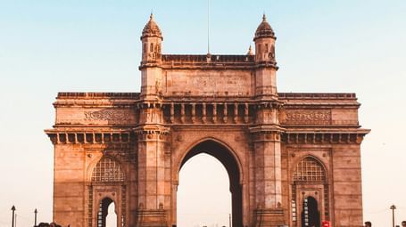 The Gateway of India monument in Mumbai, a must-visit on your list of Places in Mumbai For One-Day Trip, with people standing in front of it on a bright day.