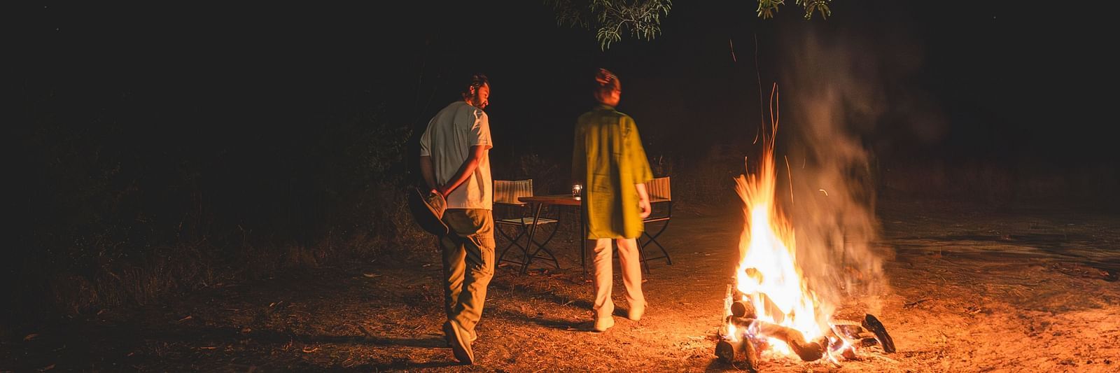 Two people walking around a bonfire at Trees N Tigers, Tadoba.