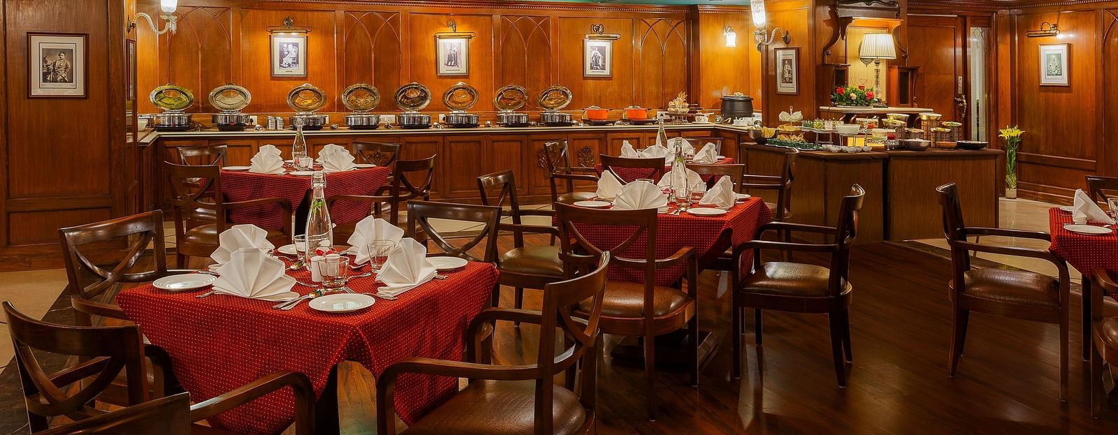 An image of Indoor view of the dining section at The Naini Retreat, Nainital, with sets of chairs and tables placed around the chandelier on the ceiling.