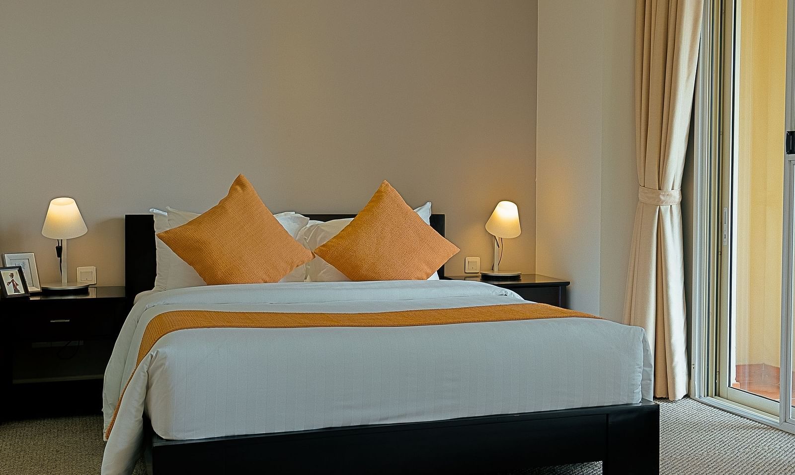 A bedroom with a bed, nightstand, and curtains | Penthouse | Central Mansions, Phnom Penh