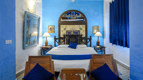 Hill Fort Kesroli 14th Century Alwar - interior view of the Hindola Mahal - Countryside View a queen size bed with a lamp on either sides and a ceiling fan