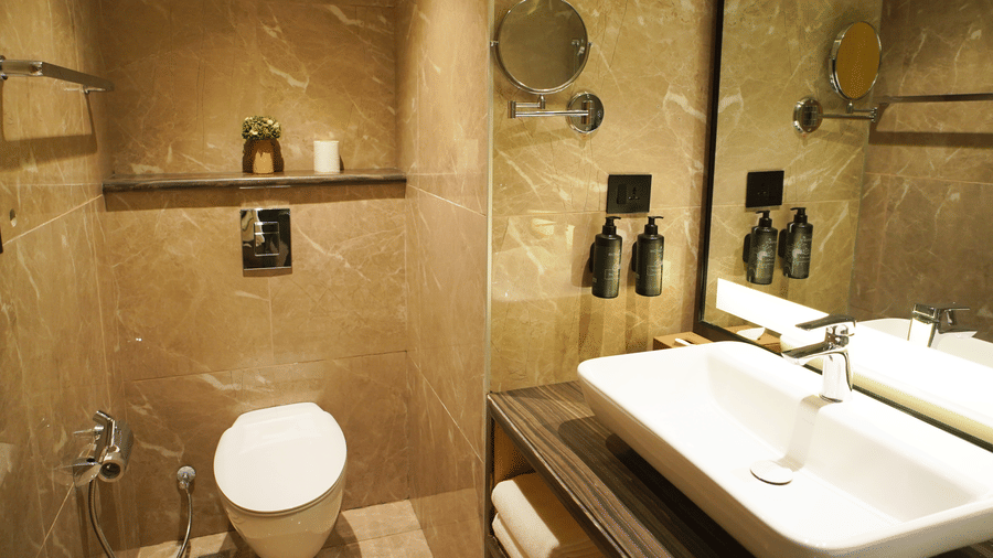 Bathroom view with toilet, wall-mounted toiletries, and a vanity mirror - Ramada Encore by Wyndham Gurugram Dwarka Expressway