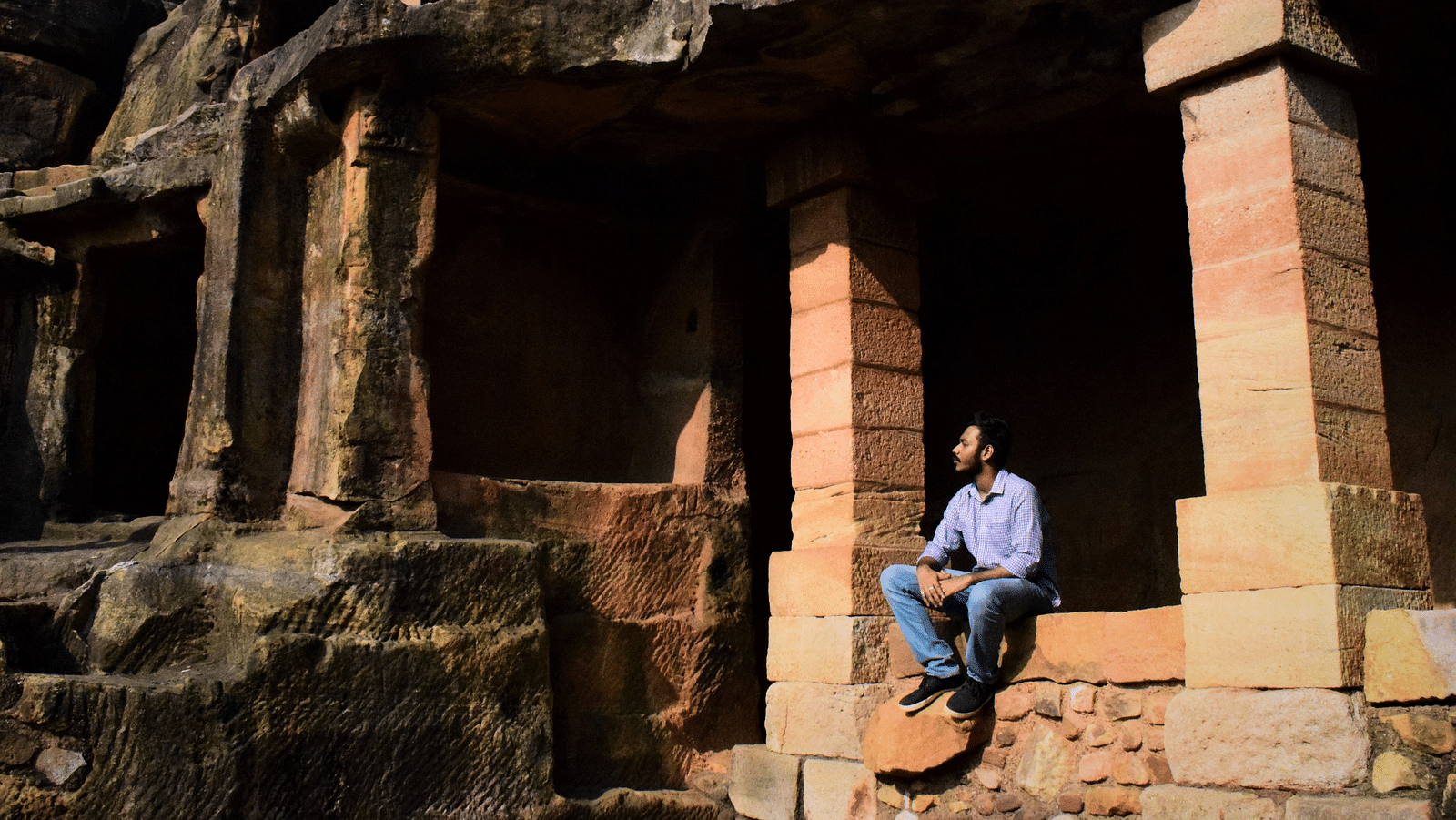 Man sitting at the entrance of a stone cave