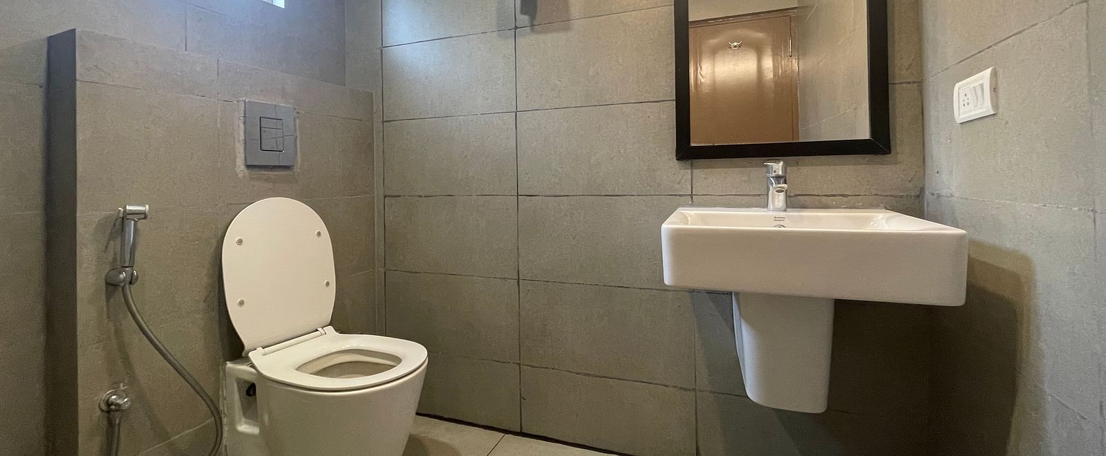 A toilet and a washbasin in the washroom at Sanctum Suites Richmond Road, Bangalore