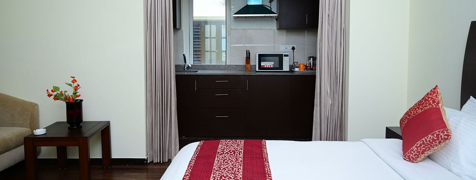 Image of a double bed with pink bedsheet and a kitchen visible from the Executive Suite at Sterling Keys by TGI