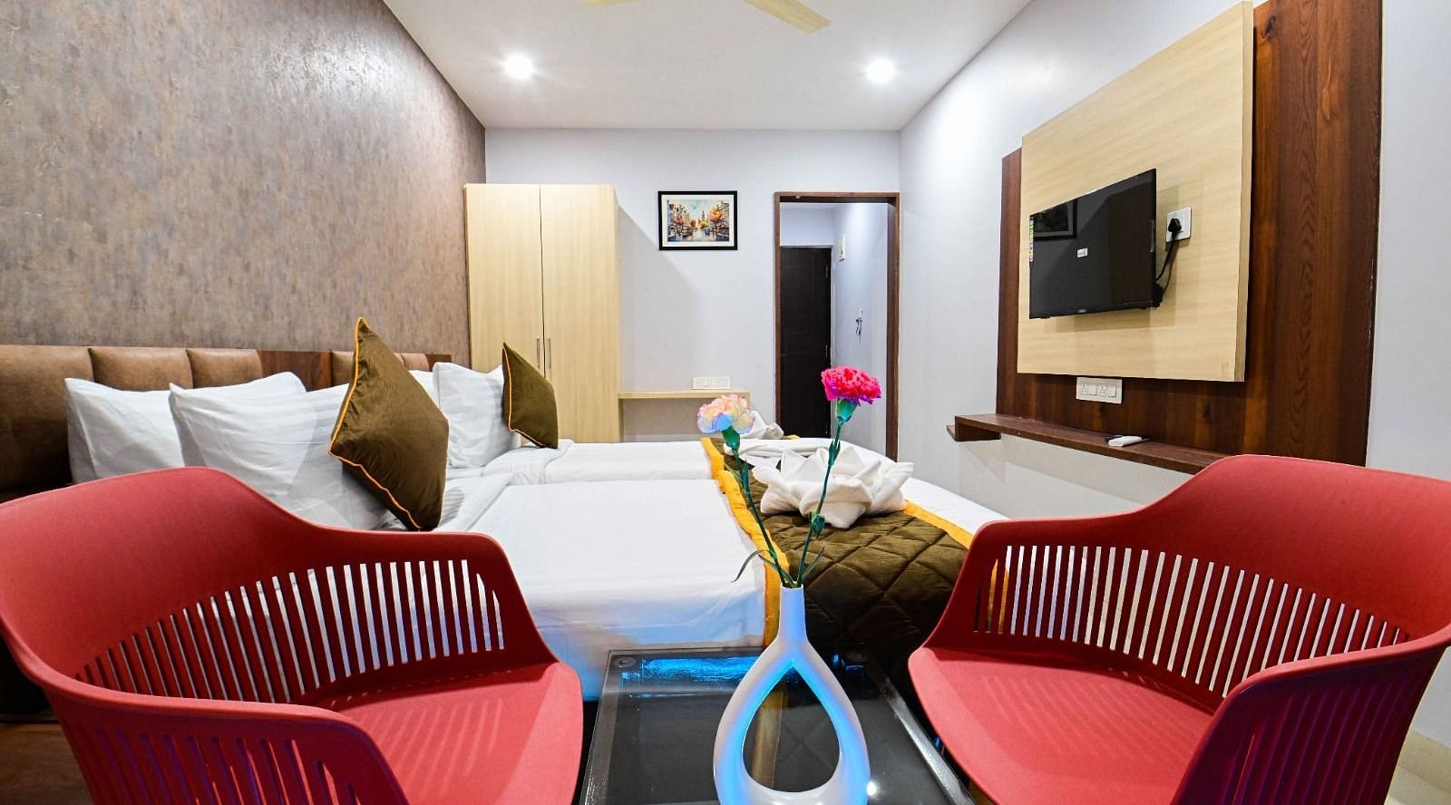 view of the  comfortable sofa setting and TV  and king size bed of Premium Balcony Room at at South Square Hotel, Bengaluru