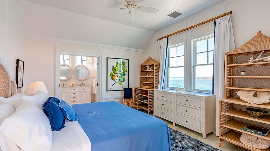 Bedroom with a blue bedspread, wooden shelving, and a ceiling fan, featuring a cozy coastal aesthetic | Abaco Inn