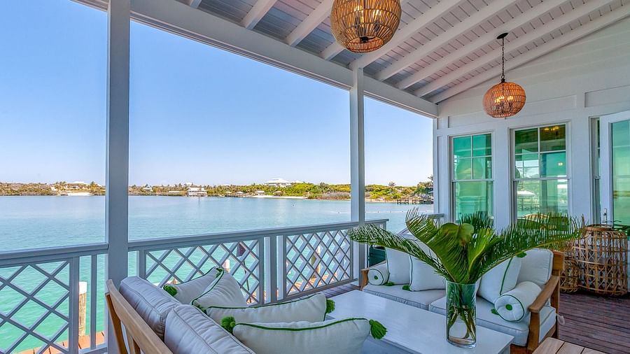 Covered porch with cushioned lounge seating, pendant lighting, and a scenic ocean view in the background | Abaco Inn