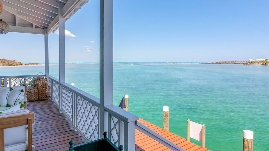 Wooden deck overlooking turquoise waters with chairs and a table under a covered porch | Abaco Inn