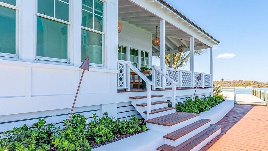 White coastal-style house with green shutters, a porch, and landscaped steps leading to the entrance | Abaco Inn