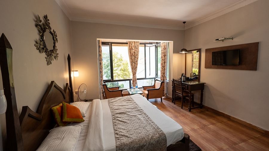 Side view of the cosy bed and a wide window at Himalaya Hotel, Nainital