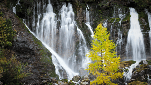 A waterfall falling on rocks with a tree in front