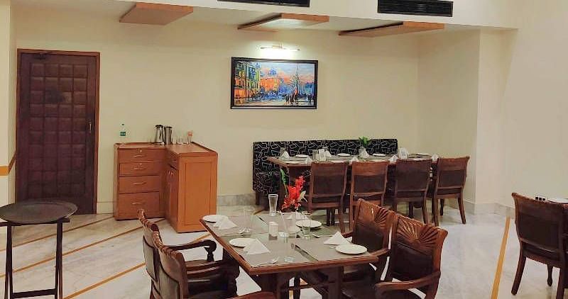 Corner view shot of a brightly lit dining area of the Gold Plate restaurant with central air-conditioning and a small cabinet in the corner of the restaurant - Hotel Gold, Panipat