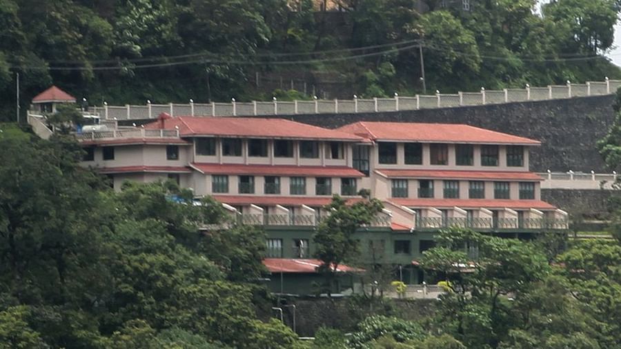 Abad Copper Castle building nestled on a green hillside, partially obscured by trees.
