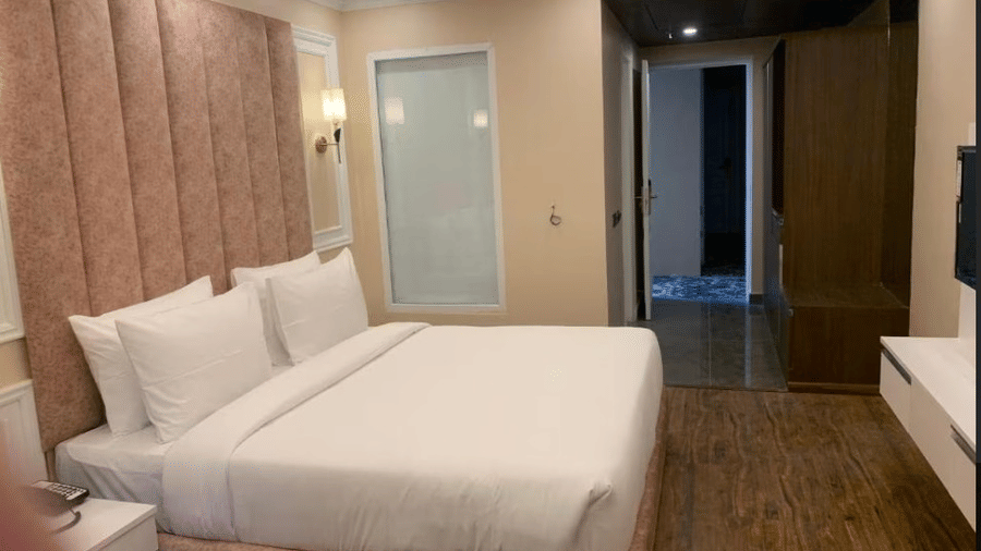 Minimalist hotel room with double bed, padded headboard, and modern decor at Claret Inn, Dalhousie.