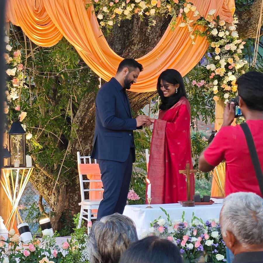 Bride and groom exchanging rings at an altar under a tree, surrounded by seated guests in an outdoor wedding in Coonoor - Ibex Stays & Trails, Coonoor (Leewood).