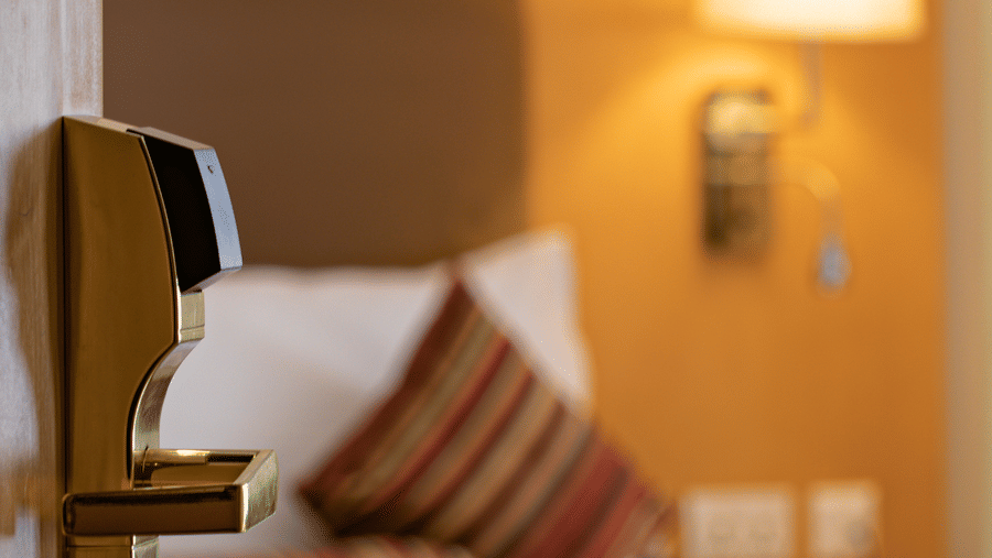 a close up of the door handle with a double bed in the background - Ramada by Wyndham Addis, Addis Ababa.