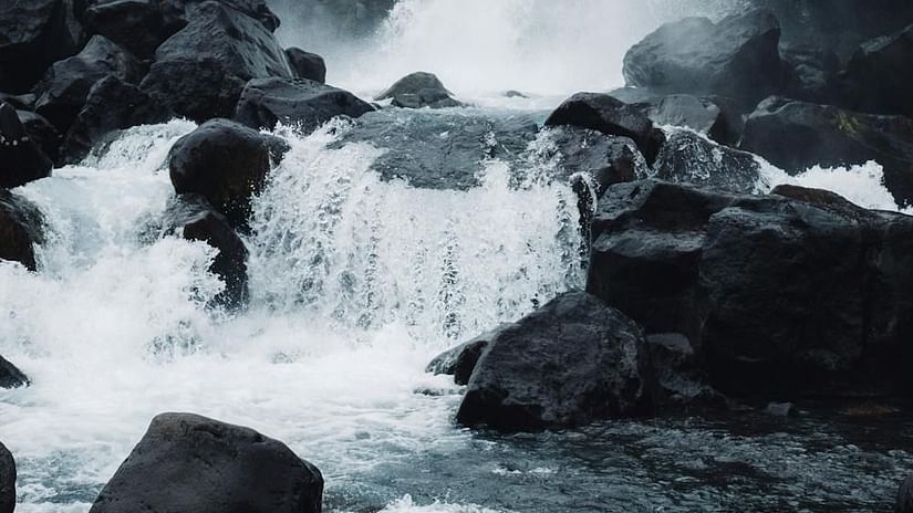 Image of a waterfall cascading through rocks with a glommy sky in the background - The Dukes Retreat, Khandala