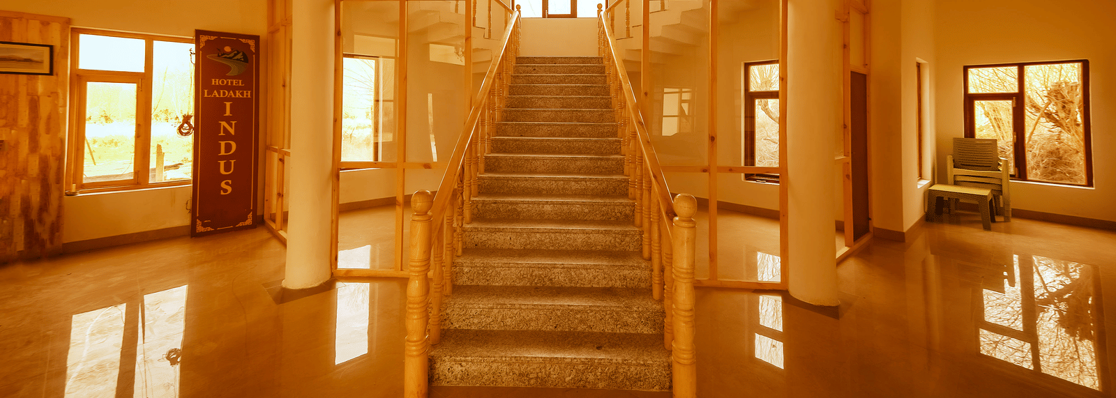 A grand wooden staircase leading upwards in a sun-drenched hallway at Indus Serenity Retreat.