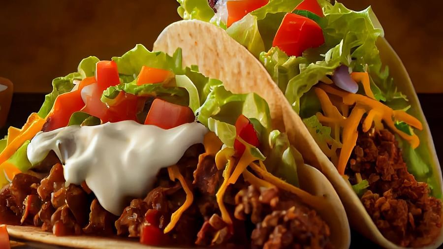 Two fully stuffed tacos with ground meat and fresh toppings on a rectangular plate - Themis Barbecue House, Ambience Mall, Gurugram
