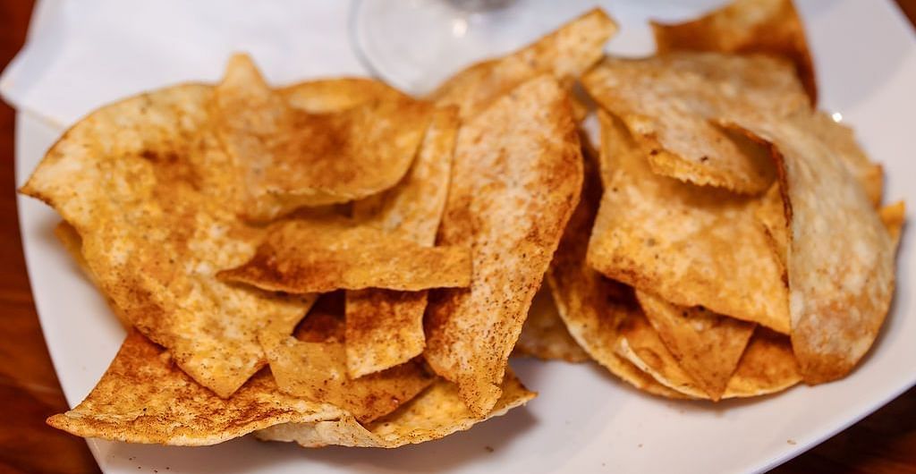 A dish served in a cocktail glass with diced avocado, tomatoes, and onions, accompanied by crispy tortilla chips on a white plate at Shaver Lake Village Hotel.