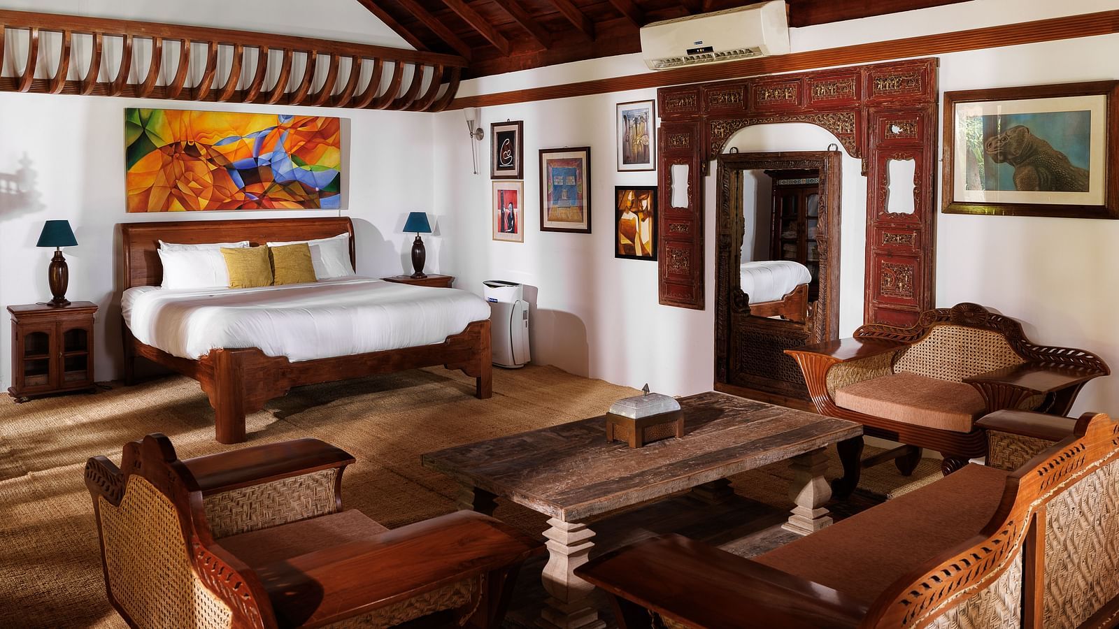 A wooden interior room with wooden furnitures such as a bed, a sofa set, a coffee table, and paintings - BluSalzz Villas - Muhamma Resort, Alleppey
