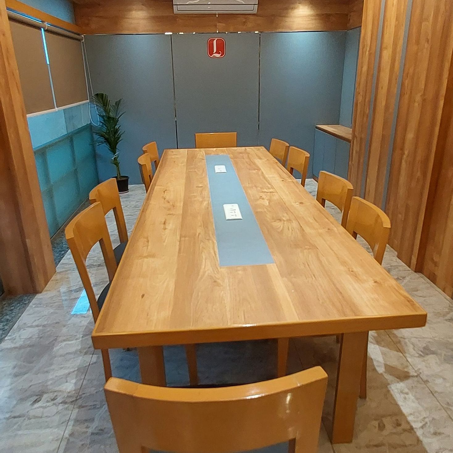 An extended conference table set in a spacious modern furnished boardroom featuring roof lights at Lords Eco Inn Dahej.