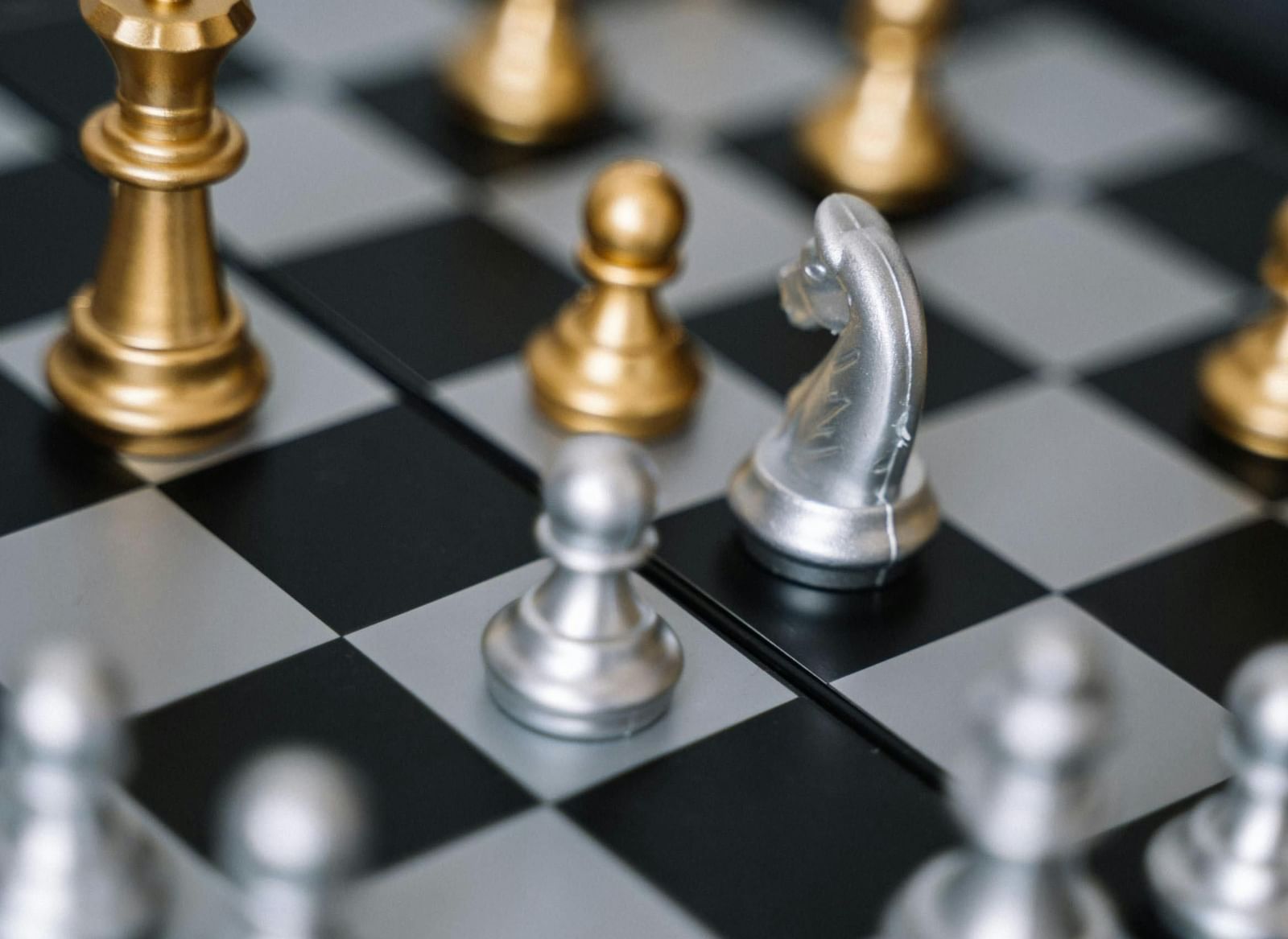 A chessboard with various gold and silver chess pieces.