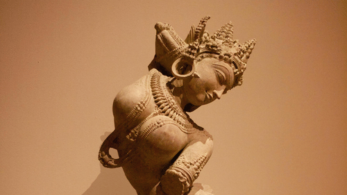 A small, ancient-looking statue of a figure in a seated or kneeling position.