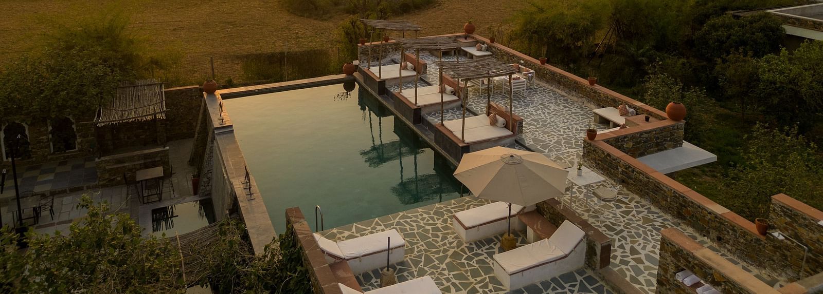 A serene sunset seen in the shot with a roof top swimming poll below it - Utsav Camp