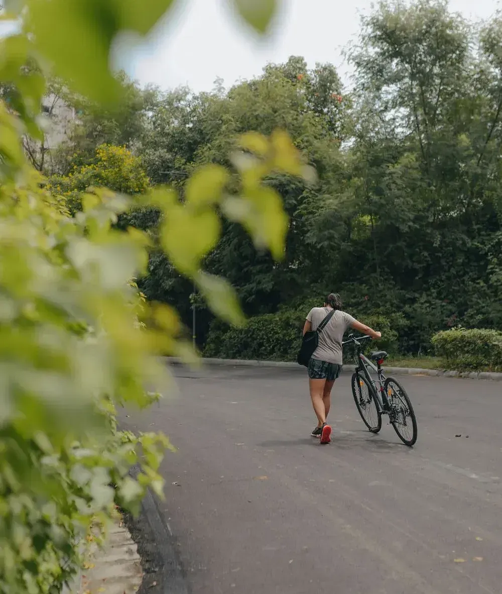 Guest cycling on a paved road surrounded by greenery at Karma Chalets.