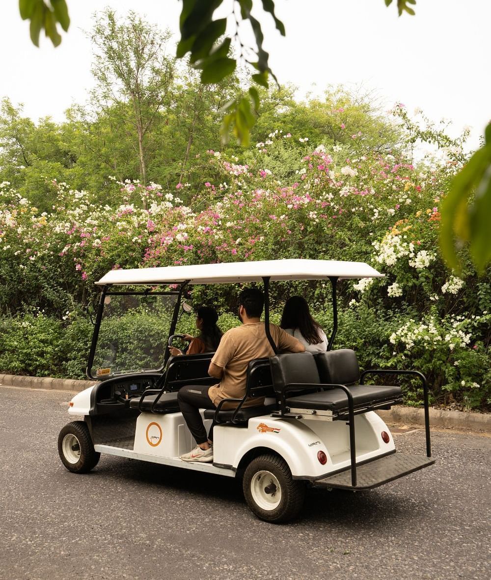 Guests riding in a white electric cart on the premises of Karma Chalets, with trees in the background.