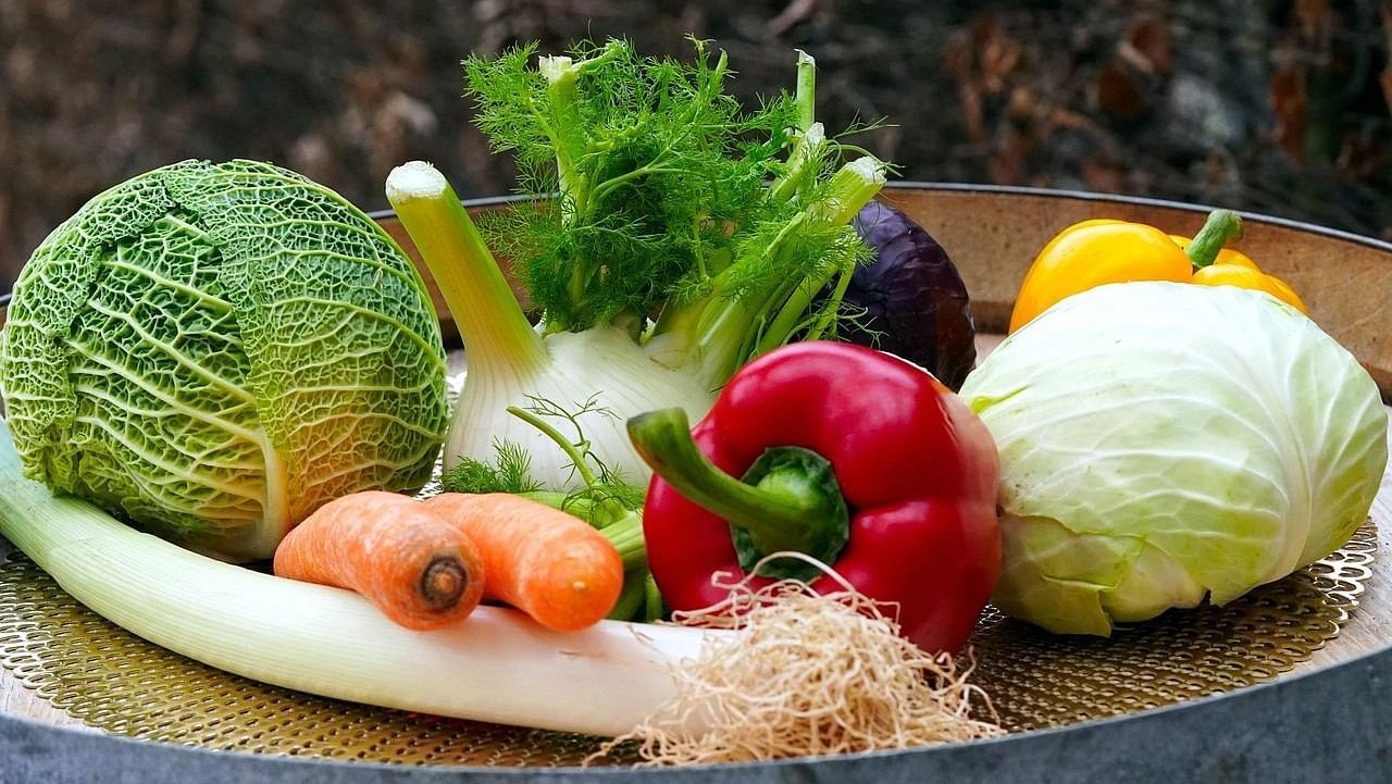 A variety of fresh vegetables including cabbage, capsicum, carrot, and lettuce arranged on a table.