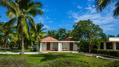 Golf Vista Cottage exterior surrounded by palm trees and lush green lawns at Chariot Beach Resorts, offering a serene tropical setting