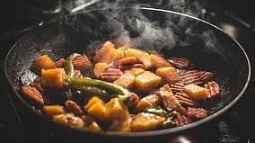  Steam rises from a sizzling pan filled with a spicy and colourful stir-fry, capturing the essence of flavourful cooking.