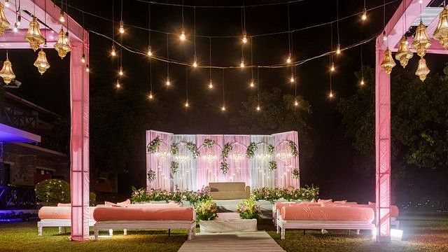 alt-text Outdoor stage decorated with flowers and string lights.