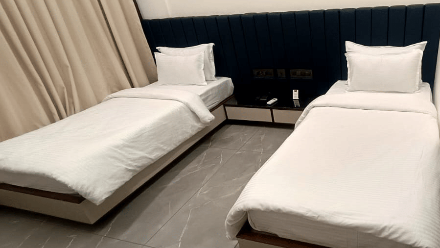 Close-up view of twin bed arrangement in a well-lit guest room - Lords Swastik Studio, Kodinar