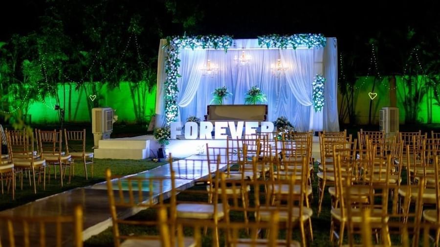 Evening view of outdoor seating facing a floral-lit stage with ‘FOREVER’ signage at Ilara Hotels & Spa, OMR, Chennai