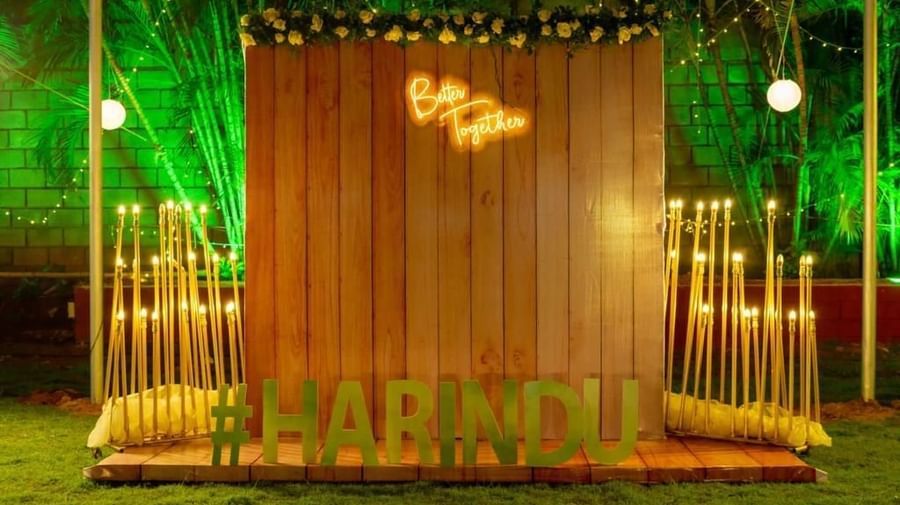 Rustic wooden photo backdrop with the couple's initials and name ‘Harindu’ in glowing lights at Ilara Hotels & Spa, OMR, Chennai