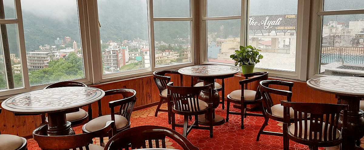 A close up shot of the restaurant with beautiful round dining table overlooking the city views from the window at Regenta Inn DLS.